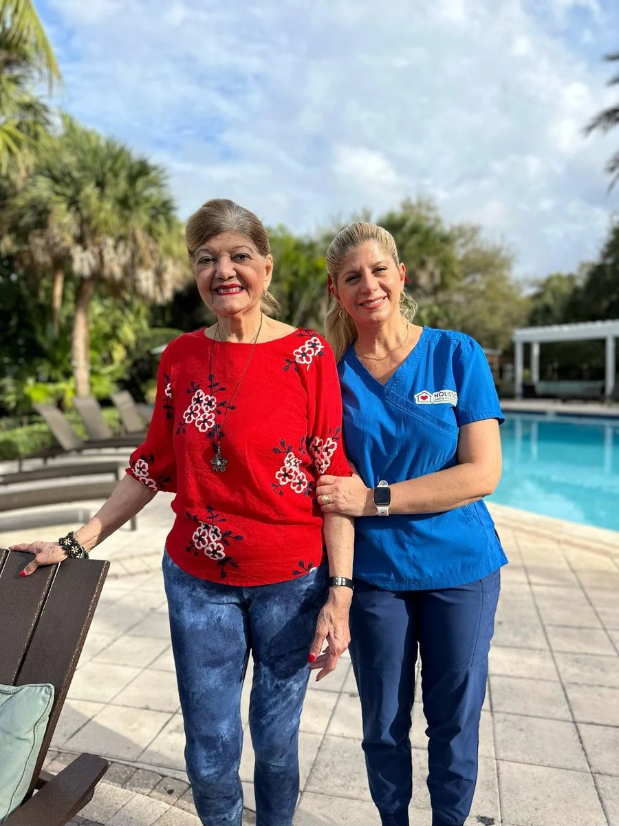 Dos mujeres posan del brazo junto a una piscina.